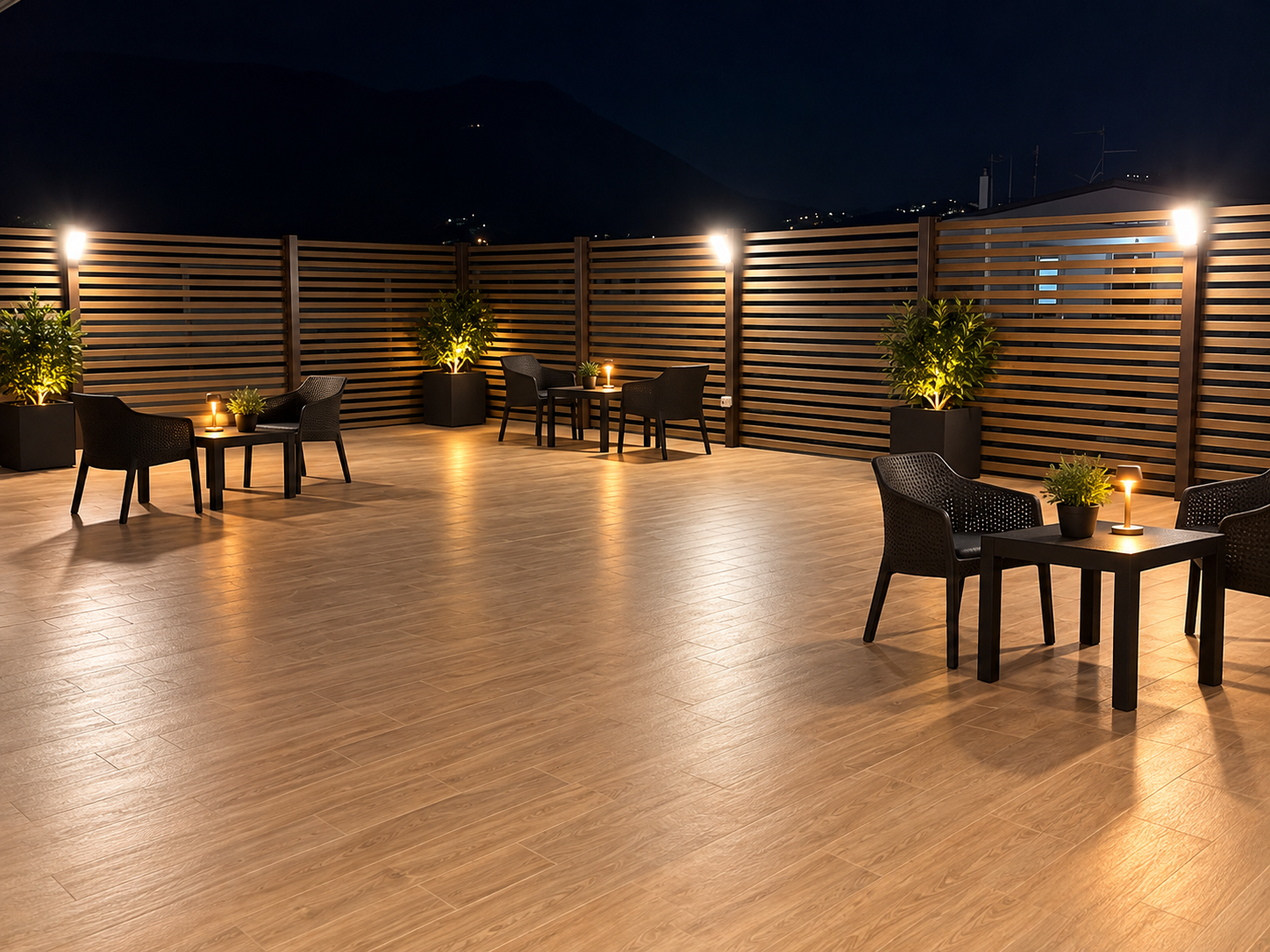 Terrazza relax con tavolini, sedute nere e piante